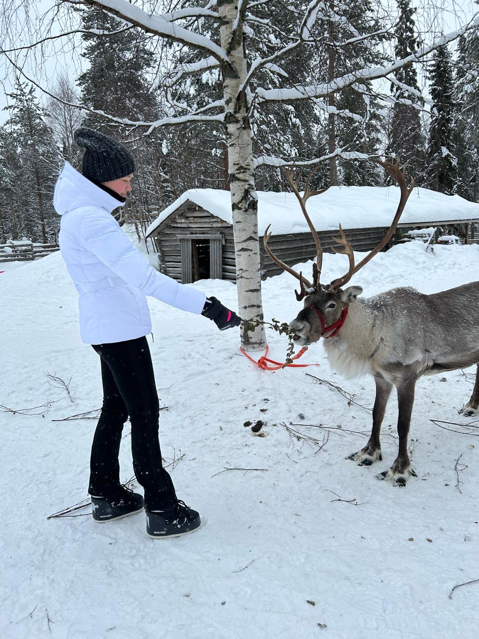 Eva Kholopova in a snowy northern landscape with a reindeer