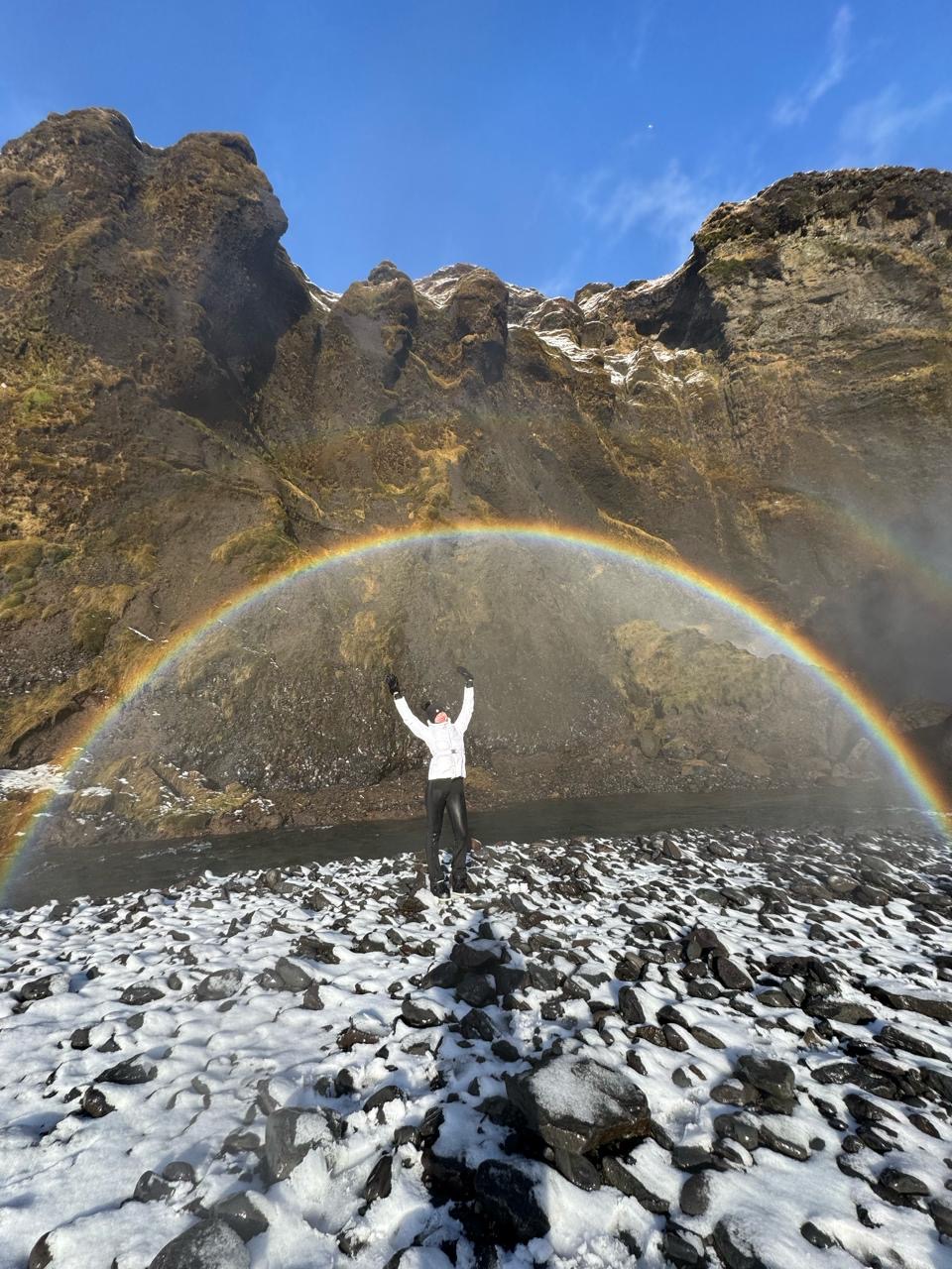 A figure beneath a rainbow in Iceland